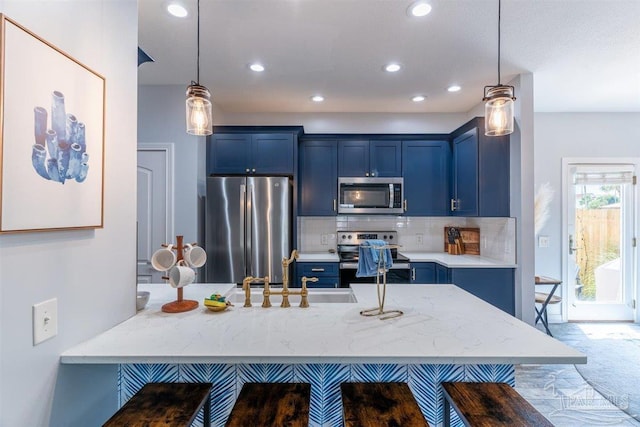 kitchen featuring blue cabinetry, stainless steel appliances, a sink, and decorative light fixtures