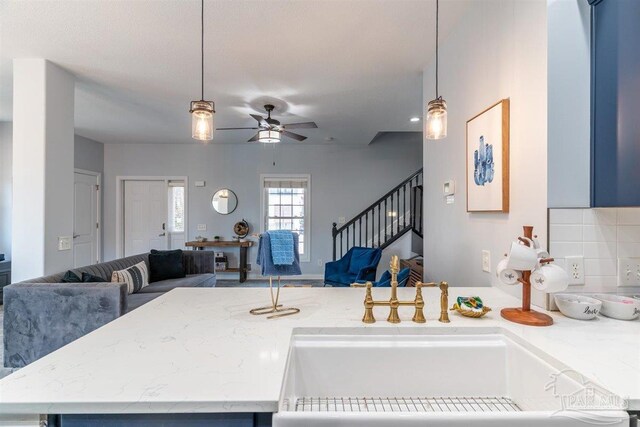 kitchen featuring ceiling fan, sink, hanging light fixtures, and decorative backsplash