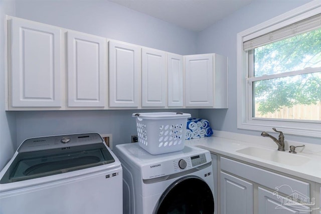 clothes washing area with independent washer and dryer, cabinet space, and a sink