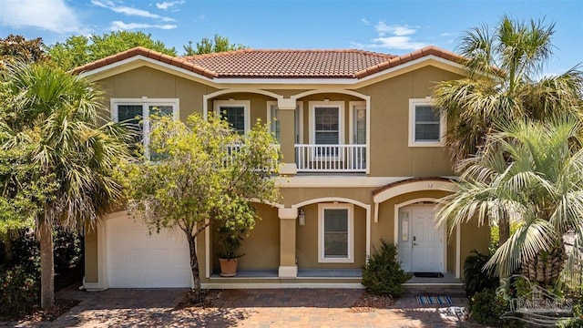 mediterranean / spanish-style home with an attached garage, a tile roof, and stucco siding