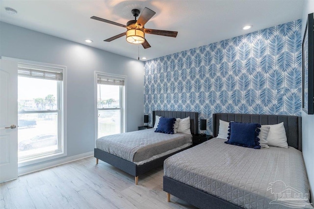 bedroom featuring recessed lighting, an accent wall, wood finished floors, a ceiling fan, and baseboards