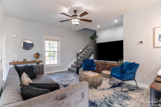 living area featuring ceiling fan, stairs, baseboards, and wood finished floors