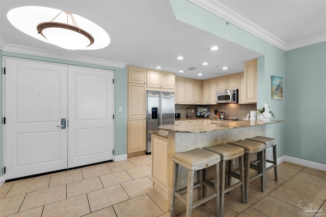 kitchen featuring a breakfast bar, ornamental molding, kitchen peninsula, stainless steel appliances, and light stone countertops