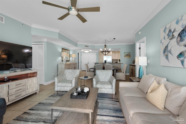 living room featuring light tile patterned flooring, ornamental molding, and ceiling fan with notable chandelier