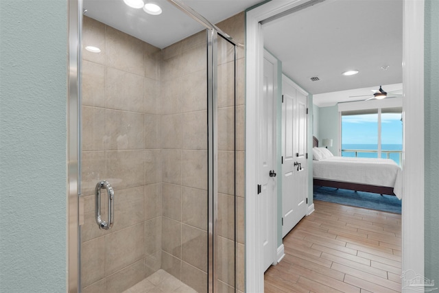 bathroom with hardwood / wood-style flooring, a shower with shower door, and a water view