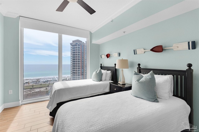 bedroom featuring crown molding, ceiling fan, a water view, wood-type flooring, and expansive windows