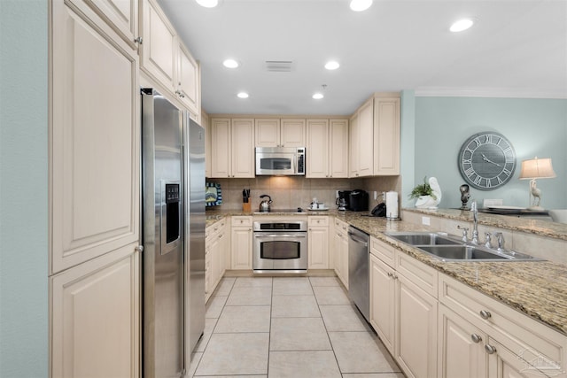 kitchen with sink, light tile patterned floors, appliances with stainless steel finishes, backsplash, and light stone counters