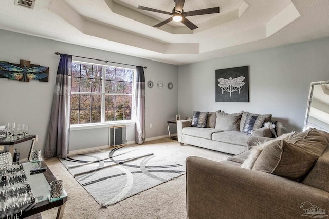 carpeted living room featuring ceiling fan and a raised ceiling