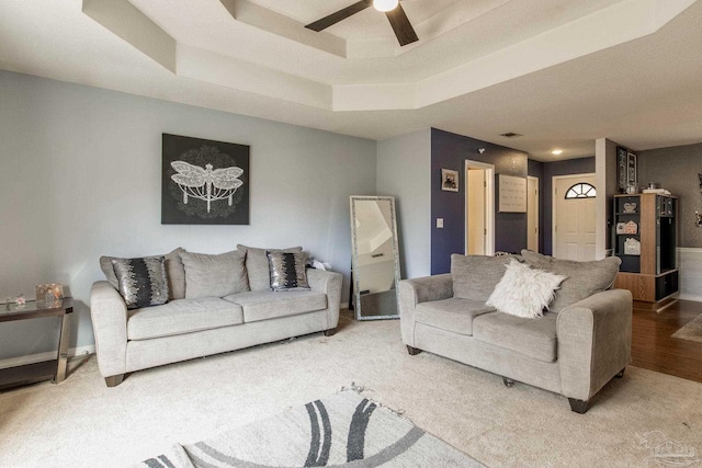 living room featuring ceiling fan, a raised ceiling, and hardwood / wood-style floors