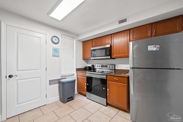 kitchen with brown cabinets, visible vents, stainless steel appliances, and light tile patterned flooring