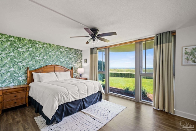 bedroom with wallpapered walls, baseboards, dark wood-type flooring, access to outside, and a textured ceiling