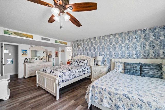 bedroom with dark wood finished floors, visible vents, ceiling fan, baseboards, and wallpapered walls