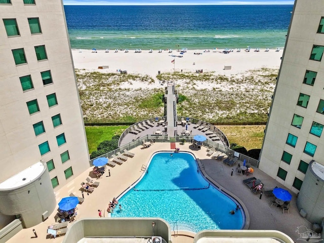 community pool featuring a water view, a patio area, and a view of the beach