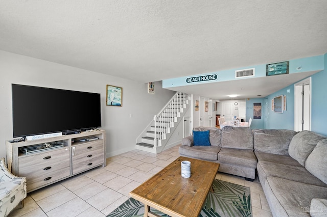 living room with visible vents, stairway, light tile patterned flooring, a textured ceiling, and baseboards