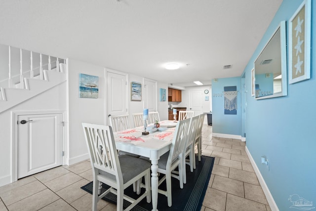 dining space featuring visible vents, stairway, baseboards, and light tile patterned floors