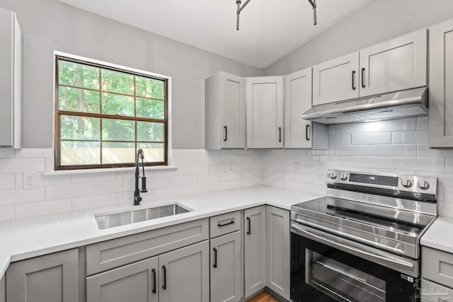 kitchen featuring under cabinet range hood, stainless steel electric range, and gray cabinetry