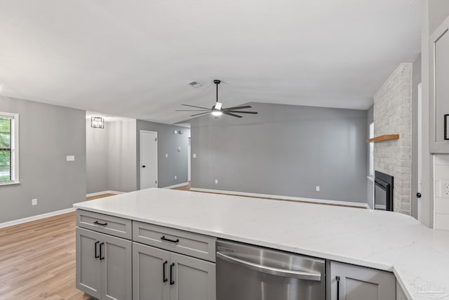 kitchen with ceiling fan, vaulted ceiling, dishwasher, gray cabinetry, and light wood-style flooring