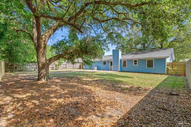 back of house featuring a lawn, a chimney, and a fenced backyard