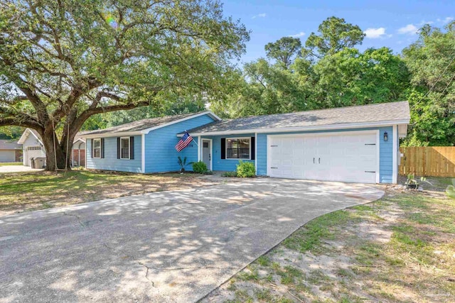 view of front of house featuring an attached garage, fence, and driveway