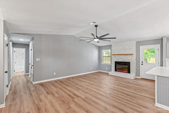 unfurnished living room with a healthy amount of sunlight, a ceiling fan, light wood-style flooring, and a brick fireplace