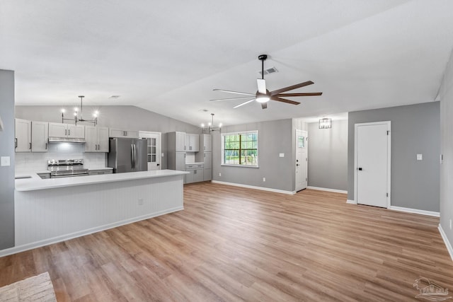 kitchen with lofted ceiling, light countertops, light wood finished floors, ceiling fan with notable chandelier, and stainless steel appliances