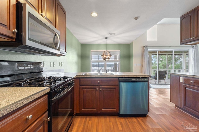 kitchen with stainless steel appliances, sink, light wood-type flooring, and kitchen peninsula