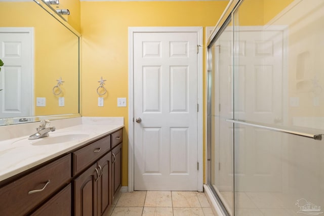 bathroom with a shower with door, vanity, and tile patterned floors