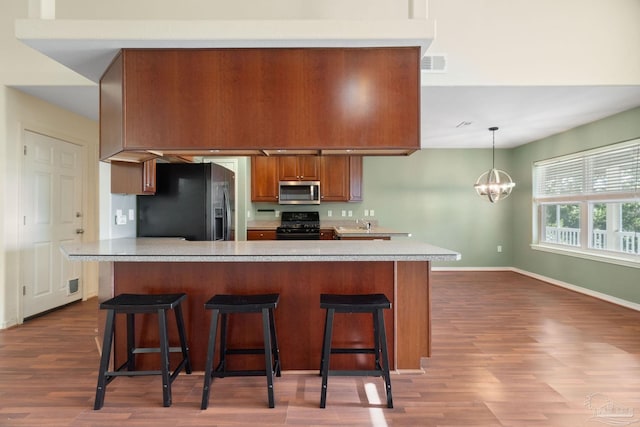 kitchen with a breakfast bar, an inviting chandelier, decorative light fixtures, hardwood / wood-style floors, and black appliances