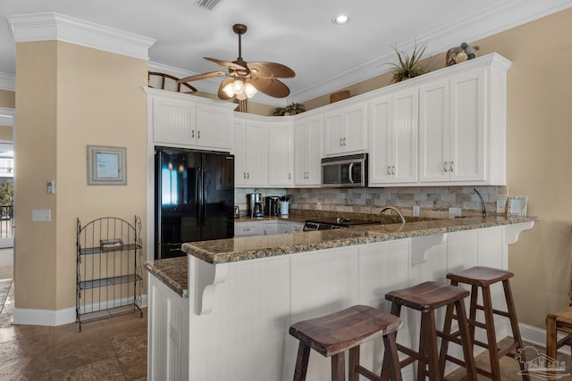 kitchen with dark tile patterned floors, kitchen peninsula, backsplash, ceiling fan, and black fridge