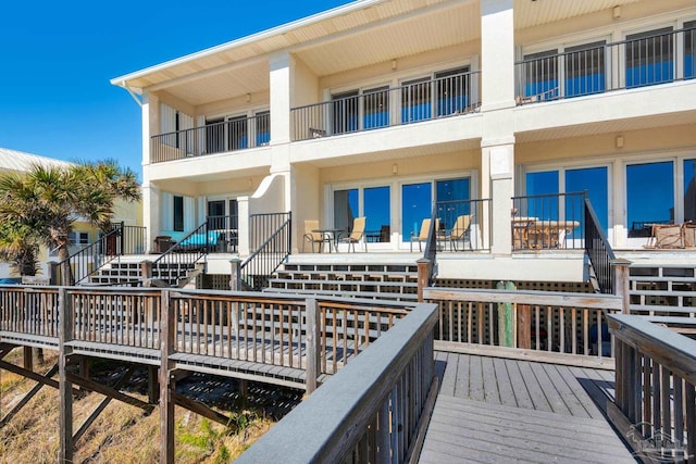 back of house featuring a balcony and a wooden deck