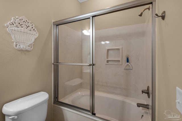 bathroom with toilet and shower / bath combination with glass door