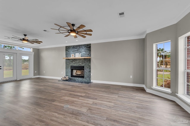 unfurnished living room with ornamental molding, a stone fireplace, hardwood / wood-style floors, and ceiling fan