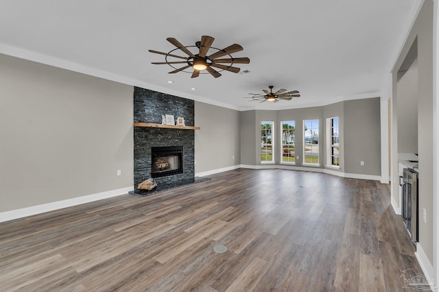 unfurnished living room with crown molding, ceiling fan, wood-type flooring, and a stone fireplace