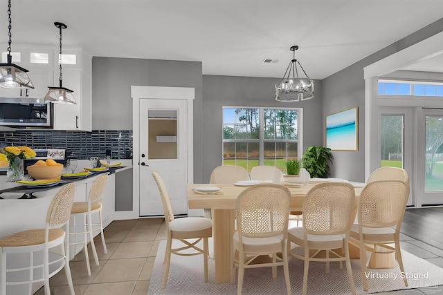 tiled dining space featuring a wealth of natural light and an inviting chandelier