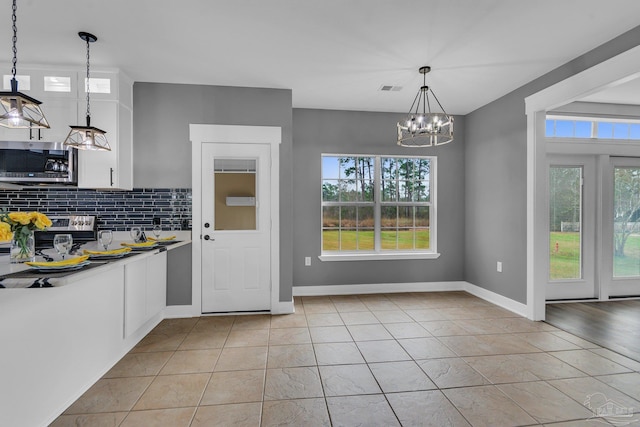 kitchen featuring white cabinetry, light tile patterned floors, pendant lighting, stainless steel appliances, and decorative backsplash