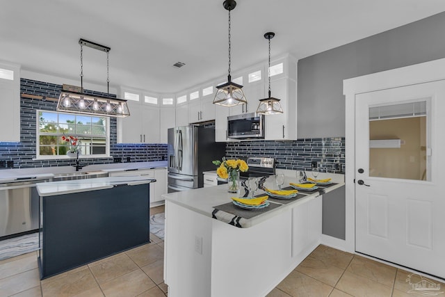 kitchen featuring sink, white cabinetry, decorative light fixtures, appliances with stainless steel finishes, and kitchen peninsula