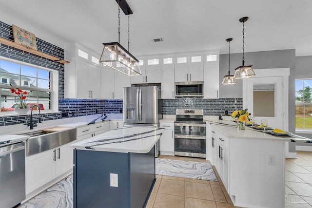 kitchen featuring appliances with stainless steel finishes, sink, a kitchen island, and white cabinets