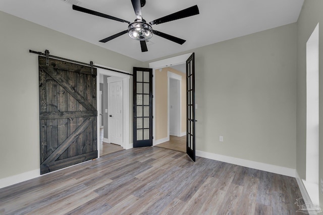 spare room with light hardwood / wood-style floors, a barn door, and ceiling fan