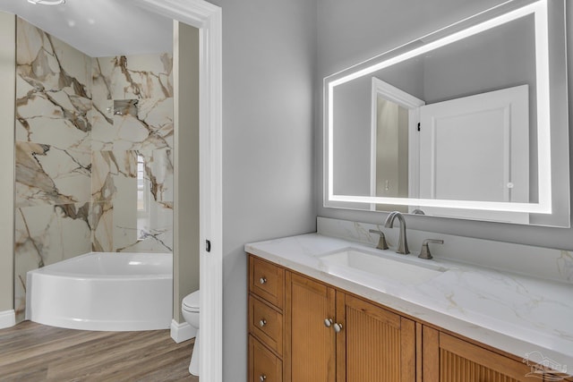 full bathroom featuring vanity, hardwood / wood-style floors, tiled shower / bath combo, and toilet