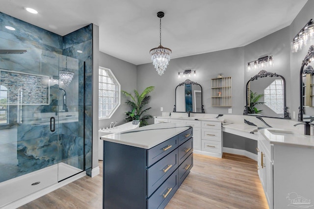 bathroom with wood-type flooring, a shower with shower door, vanity, and a notable chandelier