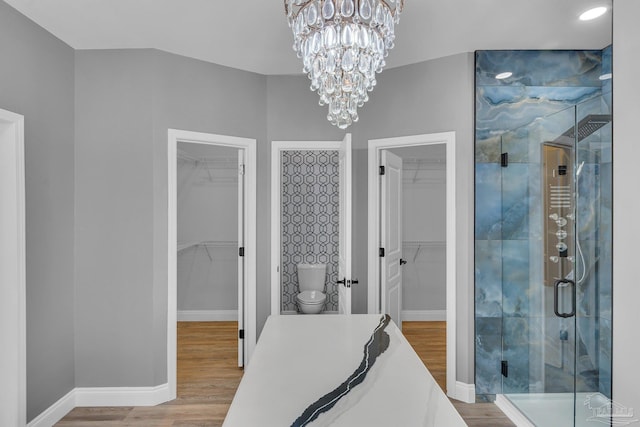 bathroom with toilet, an enclosed shower, an inviting chandelier, vanity, and hardwood / wood-style floors