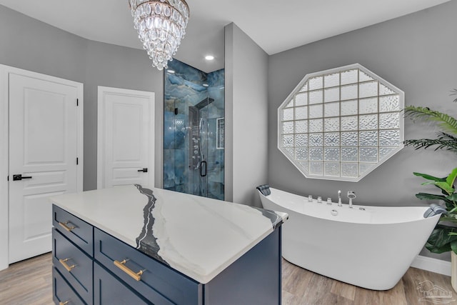 bathroom featuring independent shower and bath, wood-type flooring, plenty of natural light, and an inviting chandelier