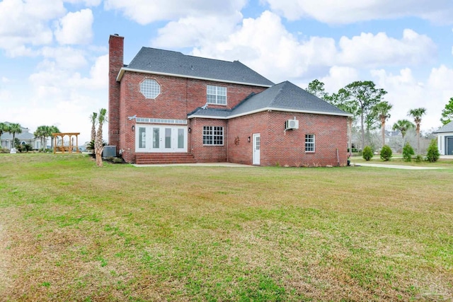 rear view of house featuring a lawn and a wall mounted AC