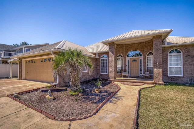 ranch-style home featuring an attached garage, metal roof, brick siding, and concrete driveway