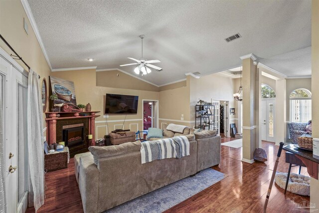 living area featuring visible vents, vaulted ceiling, a fireplace, and wood finished floors