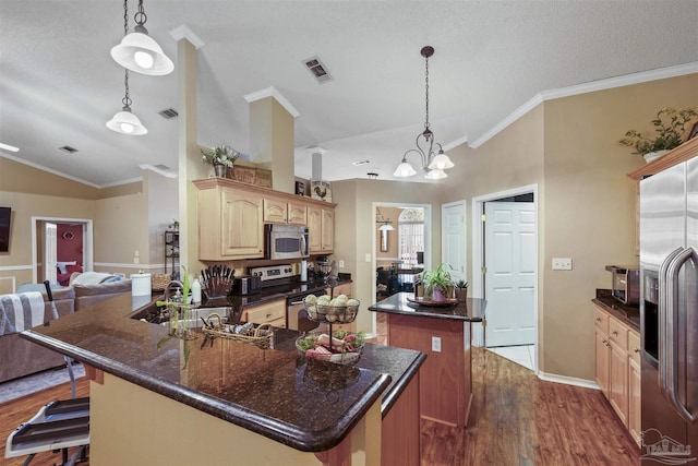 kitchen with visible vents, dark wood finished floors, appliances with stainless steel finishes, a center island, and vaulted ceiling