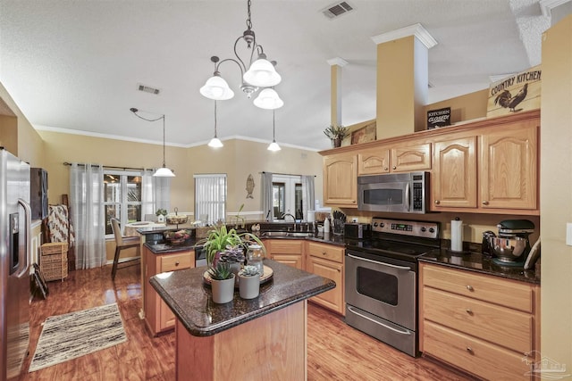 kitchen featuring visible vents, a center island, a peninsula, stainless steel appliances, and light brown cabinets