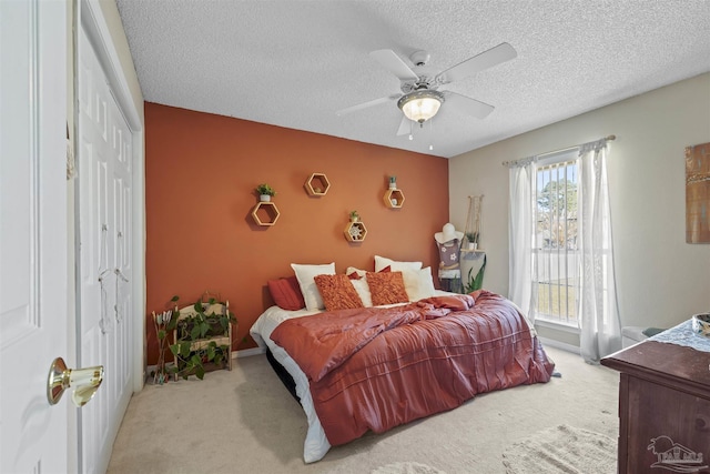 carpeted bedroom featuring a textured ceiling, a closet, a ceiling fan, and baseboards