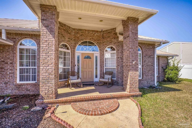 doorway to property featuring metal roof, brick siding, and a yard