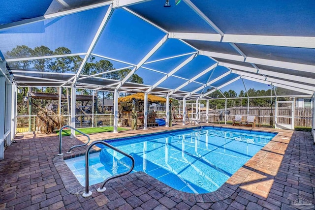 view of pool featuring glass enclosure, fence, a fenced in pool, and a patio